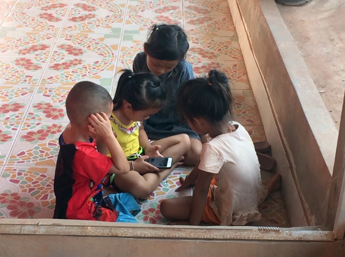 写真：スマートフォンで遊ぶラオスの子どもたち。