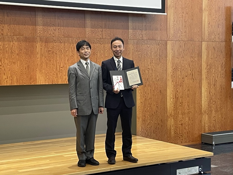 写真：日本国際経済学会 第84回全国大会における表彰式（2025年10月5日）（神事直人 日本国際経済学会会長（左）、田中清泰研究員（右）） 