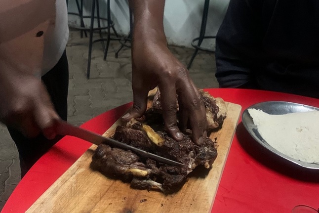 写真1　ヤギ肉のニャマ・チョマ。店員が焼いた肉の塊を切り分けてくれる。右端の白い塊はウガリ。