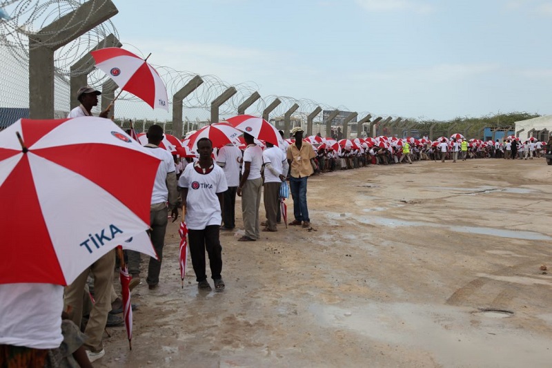トルコ国際協力調整庁（TİKA）の傘をもちながらトルコ高官の到着を待つソマリア市民